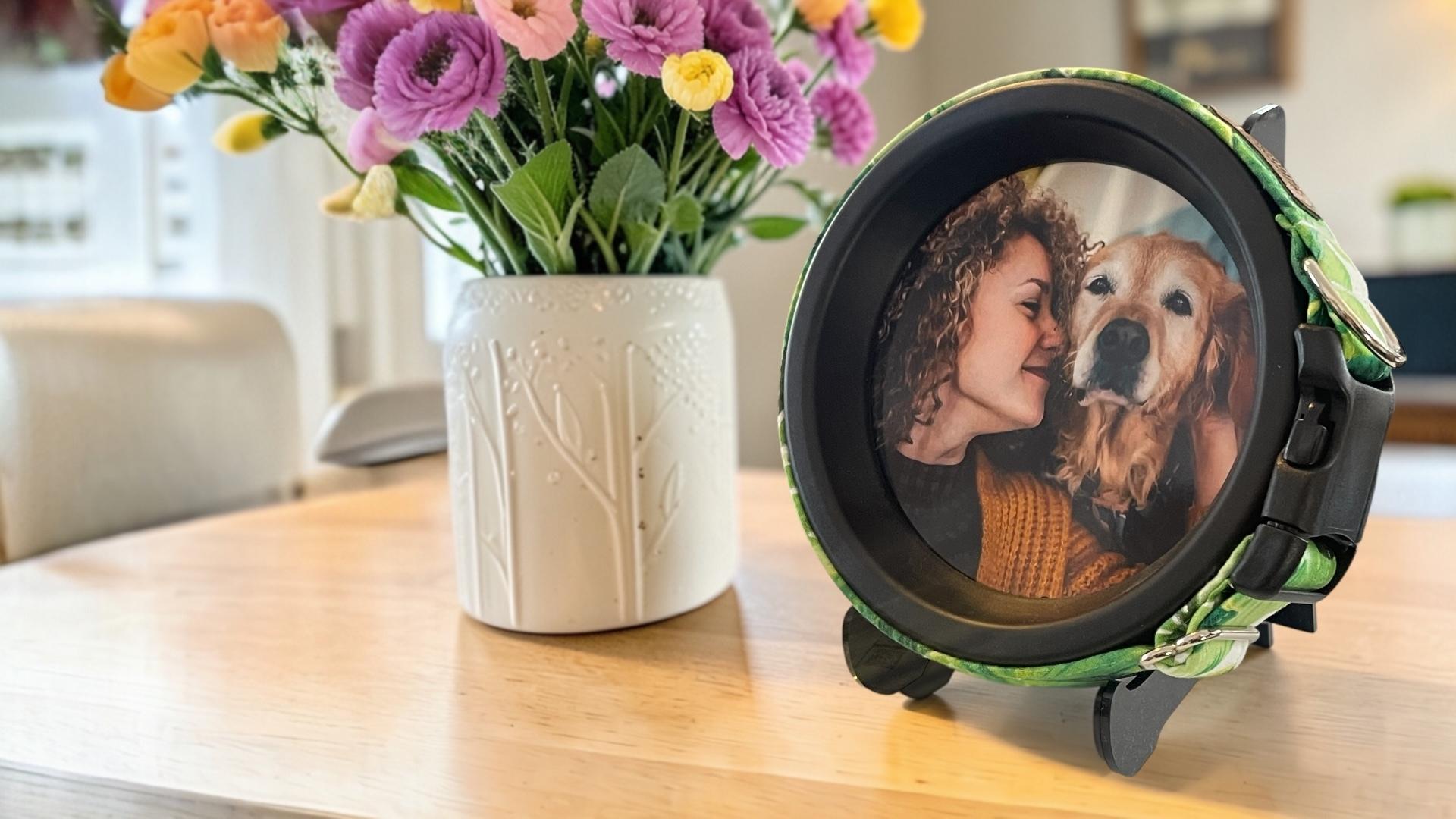 Round dog collar memorial frame photo frame with a couple and dog on a table next to a vase of flowers
